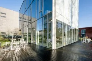 Moderne glazen gevel met terras en zitplekken aan de Fred. Roeskestraat in Amsterdam.